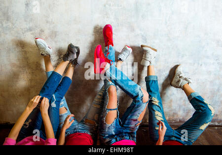 Caucasian women admiring their sneakers against wall Stock Photo