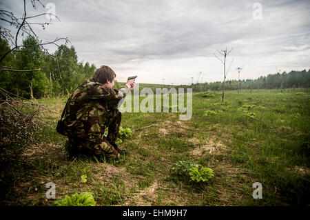 Caucasian man practicing shooting in rural field Stock Photo