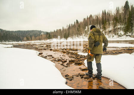 Caucasian hiker walking in rocky remote river Stock Photo