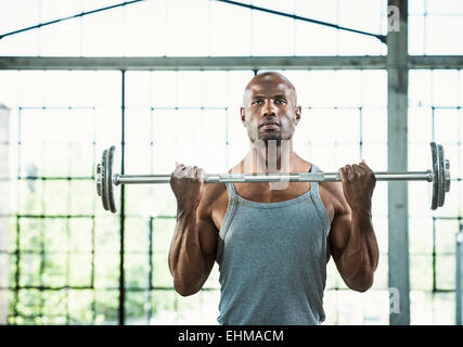 Black man lifting weights in warehouse Stock Photo