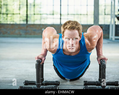 Caucasian man doing push ups in warehouse gym