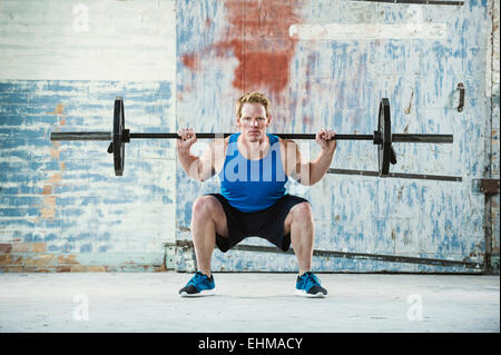 Caucasian man lifting weights in warehouse Stock Photo