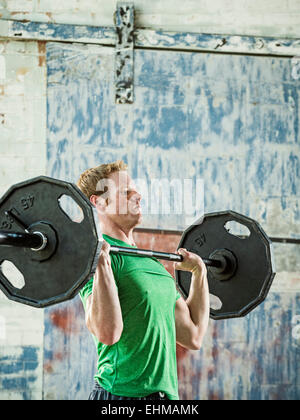 Caucasian man lifting weights in warehouse Stock Photo