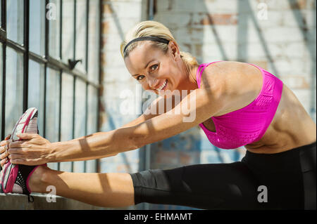 Caucasian woman stretching in warehouse Stock Photo