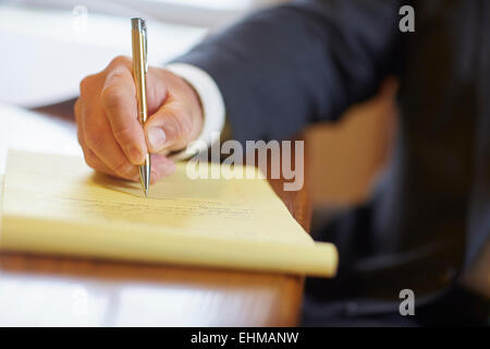 Mixed race businessman writing on notepad at desk Stock Photo