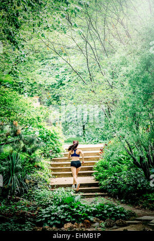 Caucasian woman running on staircase in park Stock Photo