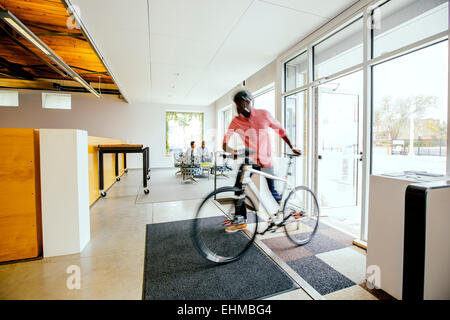 Blurred view of businessman pushing bicycle into office Stock Photo