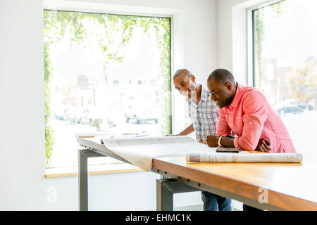 Businessmen reading blueprints in office Stock Photo
