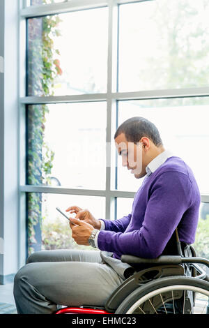 Businessman in wheelchair using digital tablet in office Stock Photo