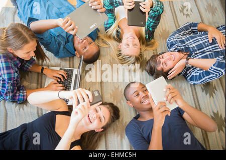 Teenagers laying on floor using technology Stock Photo