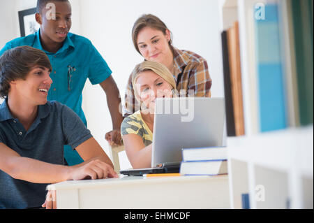 Teenagers using laptop at desk Stock Photo