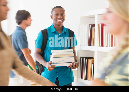 Teenage boy carrying books in library Stock Photo