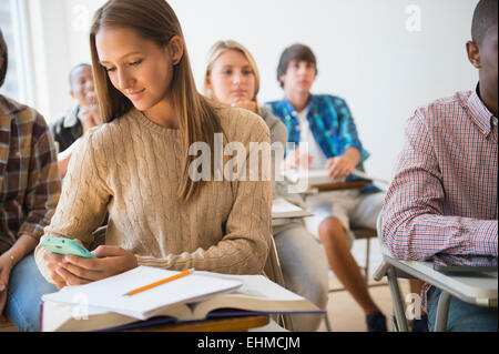 Teenage student using cell phone in classroom Stock Photo