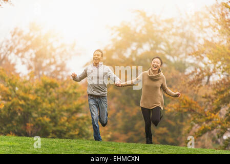 Smiling couple running in park Stock Photo