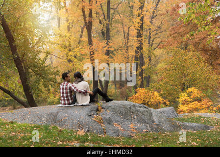 Asian couple hugging on rock in park Stock Photo