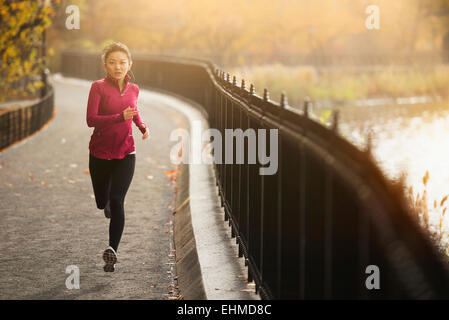 Asian woman running on waterfront path Stock Photo
