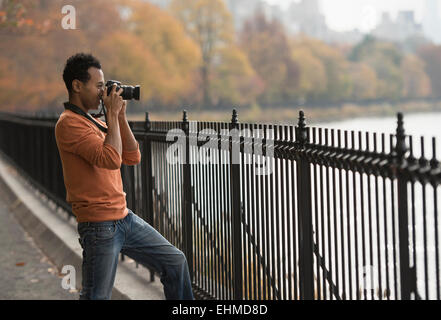 Mixed race man taking photograph on waterfront Stock Photo