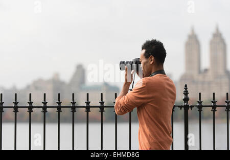 Mixed race man taking photograph on urban waterfront Stock Photo