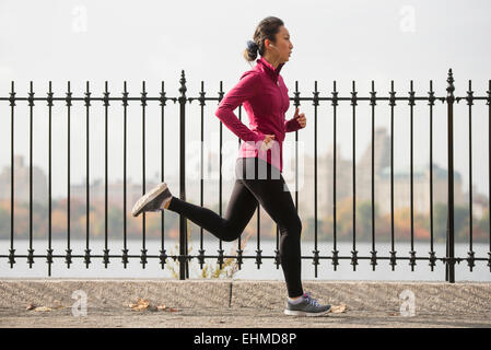Asian woman running on waterfront path Stock Photo