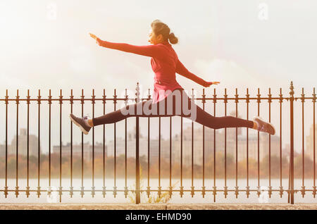 Asian woman leaping on waterfront path Stock Photo