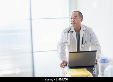 Korean doctor standing near laptop in office Stock Photo