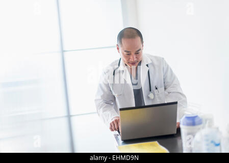 Asian doctor using laptop computer and smartphone for online ...