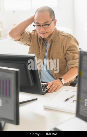 Korean businessman working on computer at office desk Stock Photo