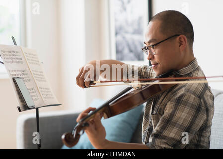 Korean musician playing violin in living room Stock Photo