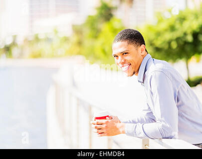 Black businessman leaning on banister at waterfront Stock Photo