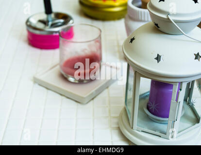 a purple candle in a lantern painted white with some stars imprinted on the cover. Stock Photo