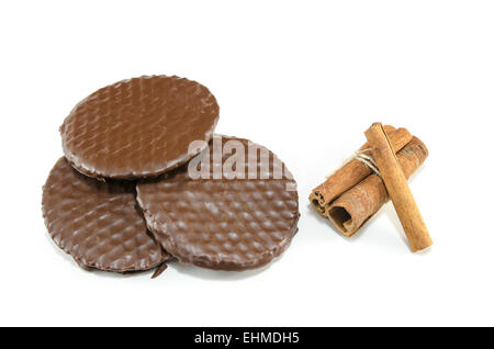 Three dark chocolate biscuits and cinnamon sticks isolated on white Stock Photo