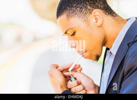 Black businessman lighting cigarette outdoors Stock Photo