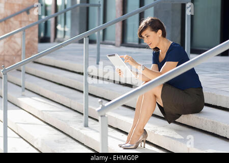 Caucasian businesswoman using digital tablet on staircase Stock Photo