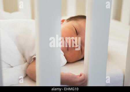 Mixed race baby sleeping in crib Stock Photo