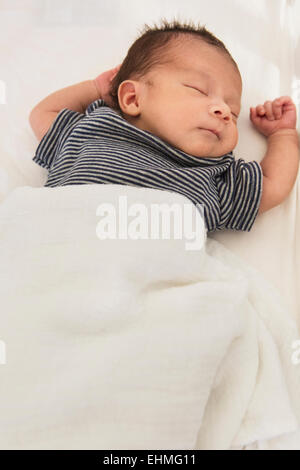 Mixed race baby sleeping on bed Stock Photo