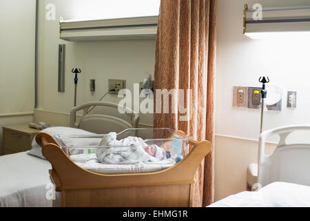 Mixed race wrapped in blanket in hospital crib Stock Photo