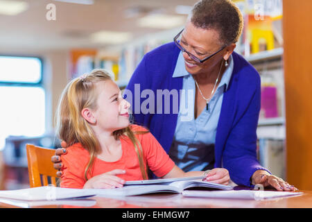 Teacher helping student in library Stock Photo