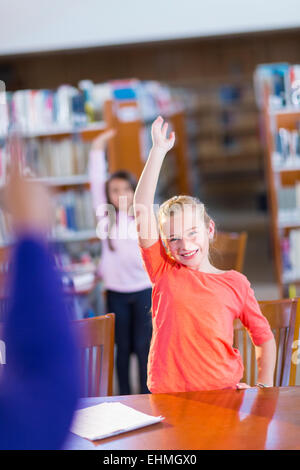 Student raising her hand in library Stock Photo