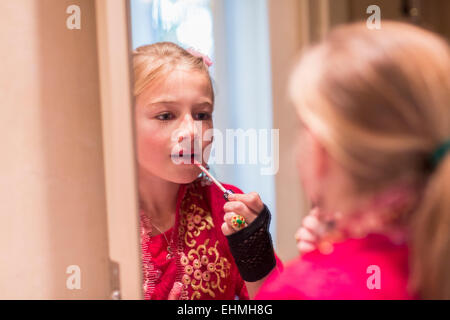 Caucasian girl applying lip gloss in mirror Stock Photo