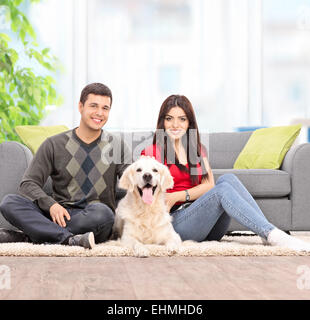 Young couple sitting on the floor with a dog at home shot with tilt and shift lens Stock Photo