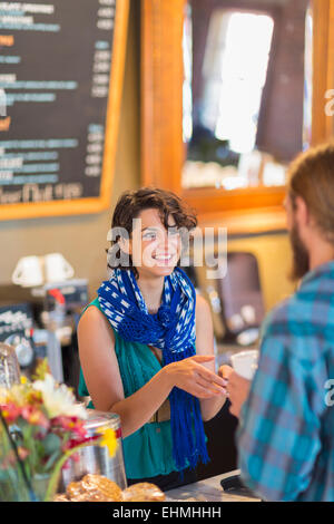 Mixed race server talking to customer in cafe Stock Photo
