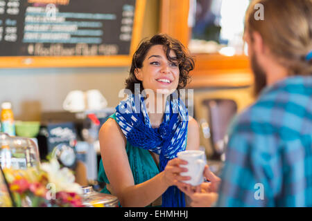 Server giving cup of coffee to customer in cafe Stock Photo