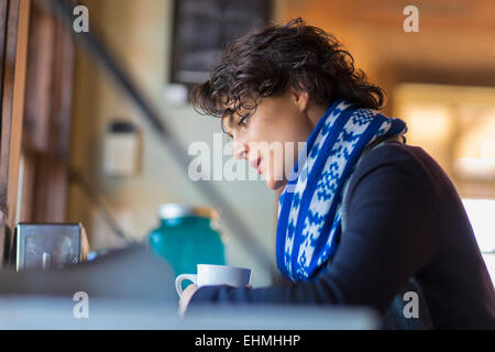 Mixed race woman drinking cup of coffee in cafe