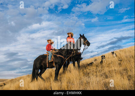 Caucasian mother and son on horseback on grassy hill Stock Photo