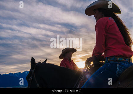 Caucasian mother and son riding horses at sunset Stock Photo