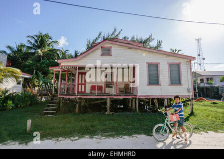 Boy on a bicycle in front of wooden house on Caye Caulker, Belize Stock Photo