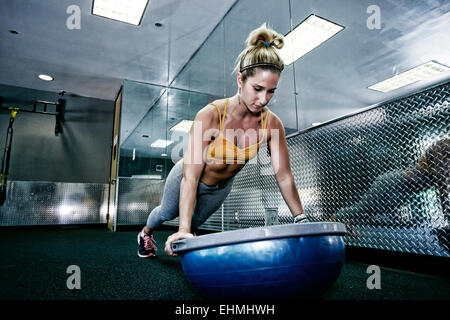 Caucasian woman doing push ups in gym Stock Photo