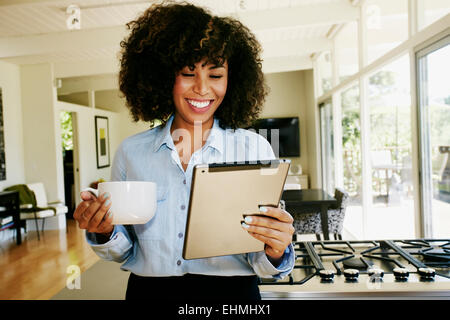 Mixed race businesswoman using digital tablet in domestic kitchen Stock Photo