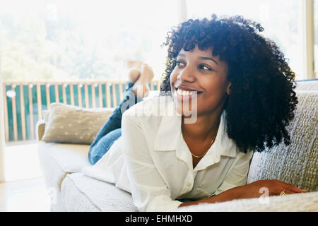 Mixed race woman laying on sofa Stock Photo