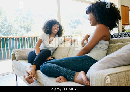 Mixed race women relaxing on sofa Stock Photo